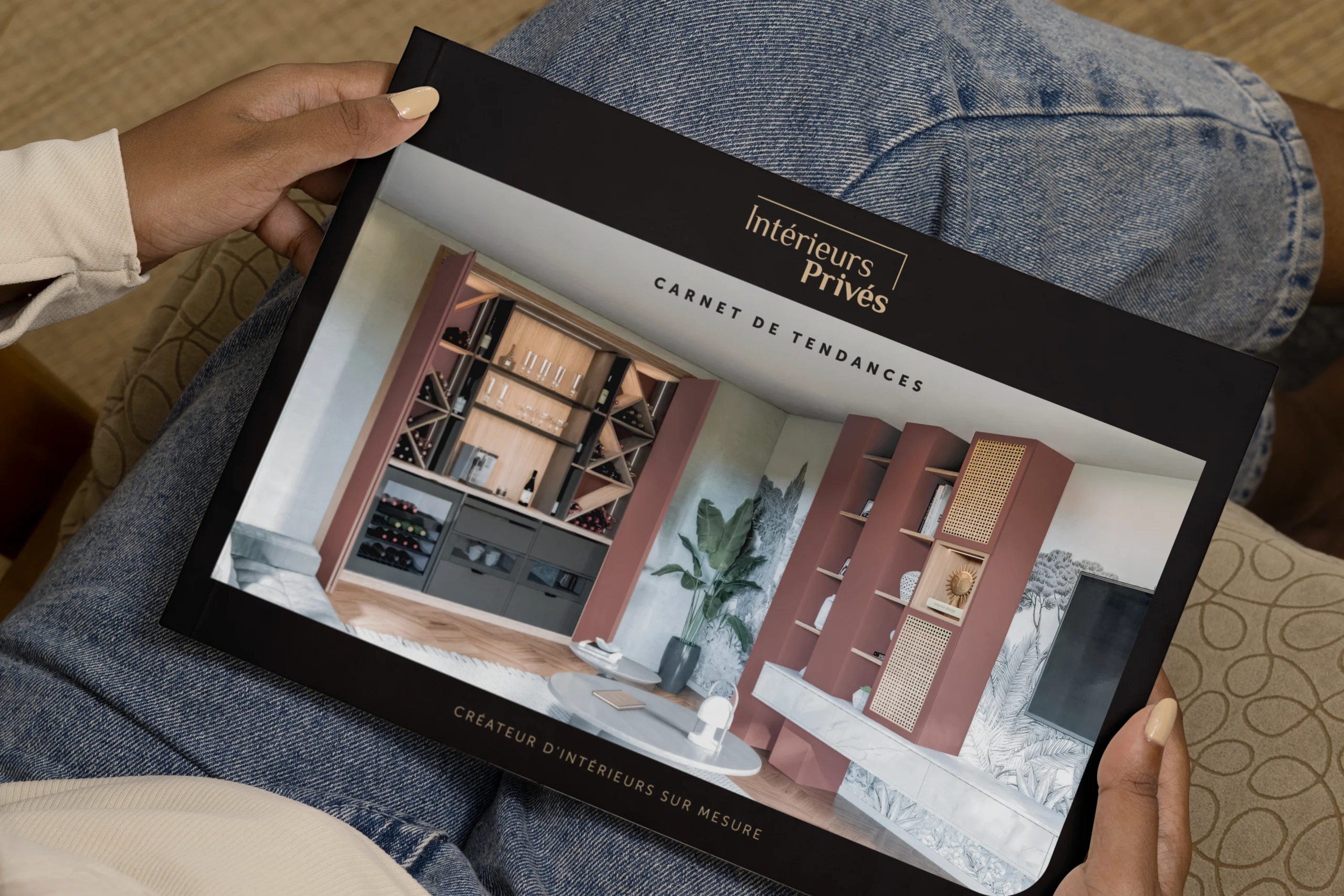 Personne tenant le carnet de tendances Intérieurs Privés présentant une couverture dédiée à l’aménagement intérieur sur mesure