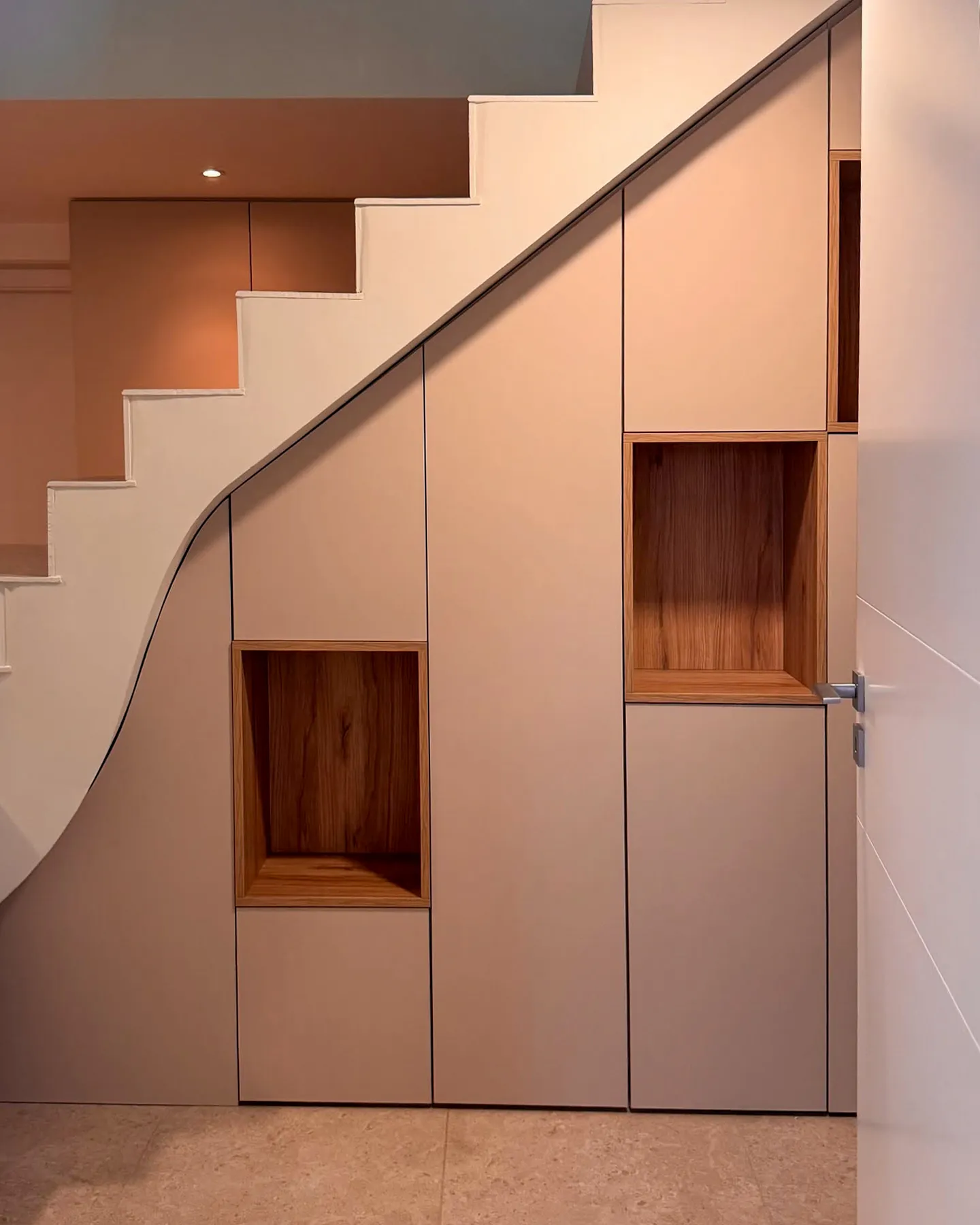 Placard sous escalier sur mesure avec portes discrètes et niches ouvertes en décor bois