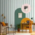 Espace bureau avec papier peint rayé, formes graphiques colorées, canapé beige et mobilier en bois.