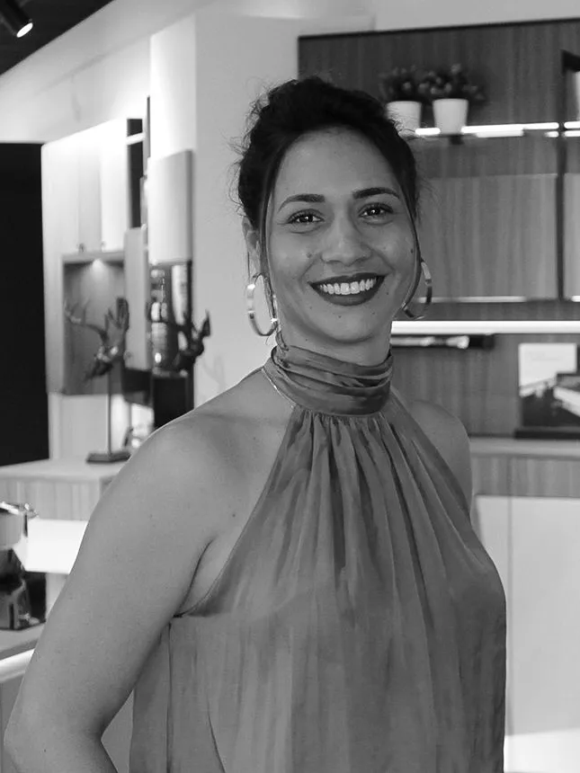 Portrait vertical d’une conceptrice Intérieurs Privés souriante dans un showroom dédié au sur mesure.