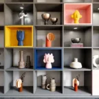 Détail d’une bibliothèque sur mesure avec niches grises, caissons colorés, objets déco et éclairage intégré.