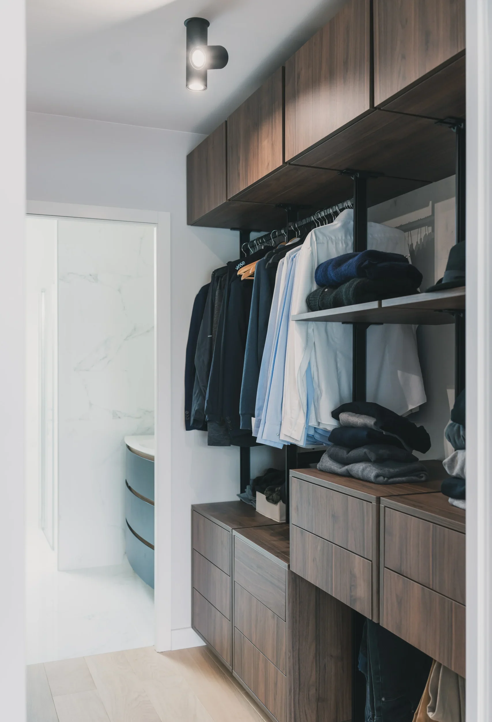 Dressing ouvert sur mesure avec penderies, étagères, tiroirs bas, façades décor bois et accès à la salle de bain.