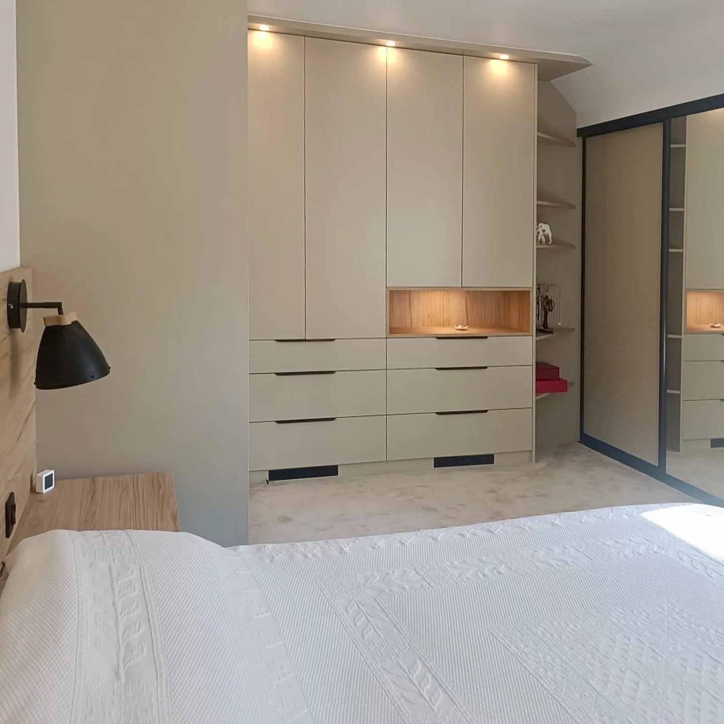 Chambre avec dressing sur mesure beige, niches bois éclairées et portes miroir, réalisé par Intérieurs Privés Sèvres.