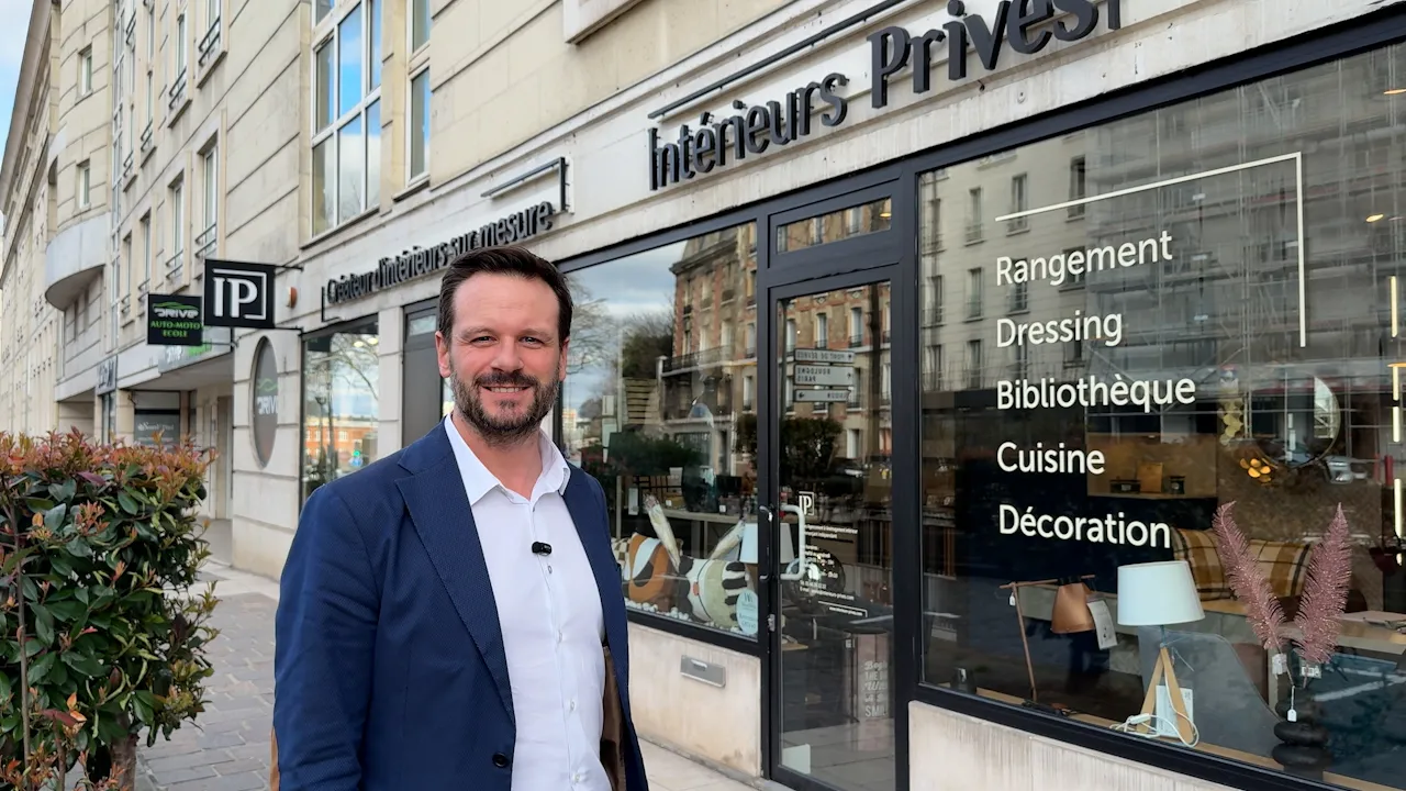 Éric Lebaud, concepteur-agenceur, souriant devant la façade lumineuse du magasin Intérieurs Privés de Sèvres, avec en vitrine les services proposés : rangement, dressing, bibliothèque, cuisine, décoration