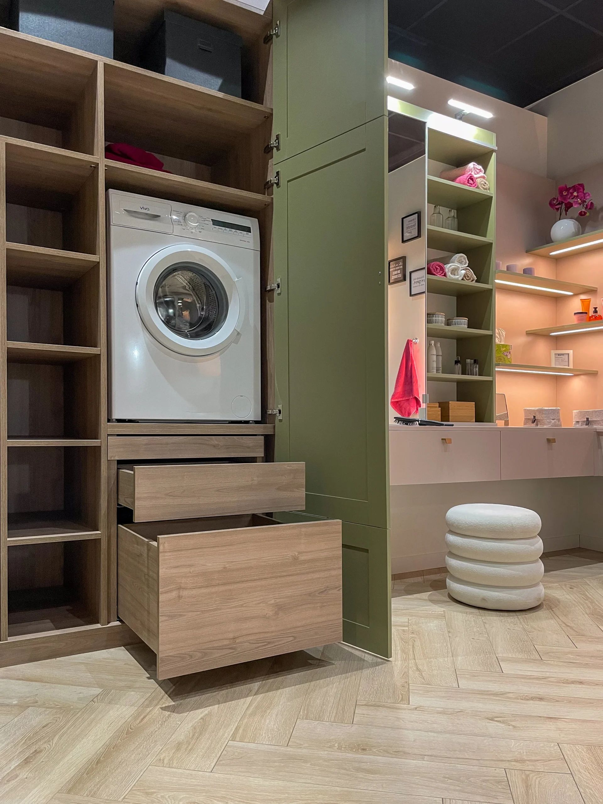 Aménagement de buanderie sur-mesure avec lave-linge encastré, tiroirs en bois et rangements vert sauge.