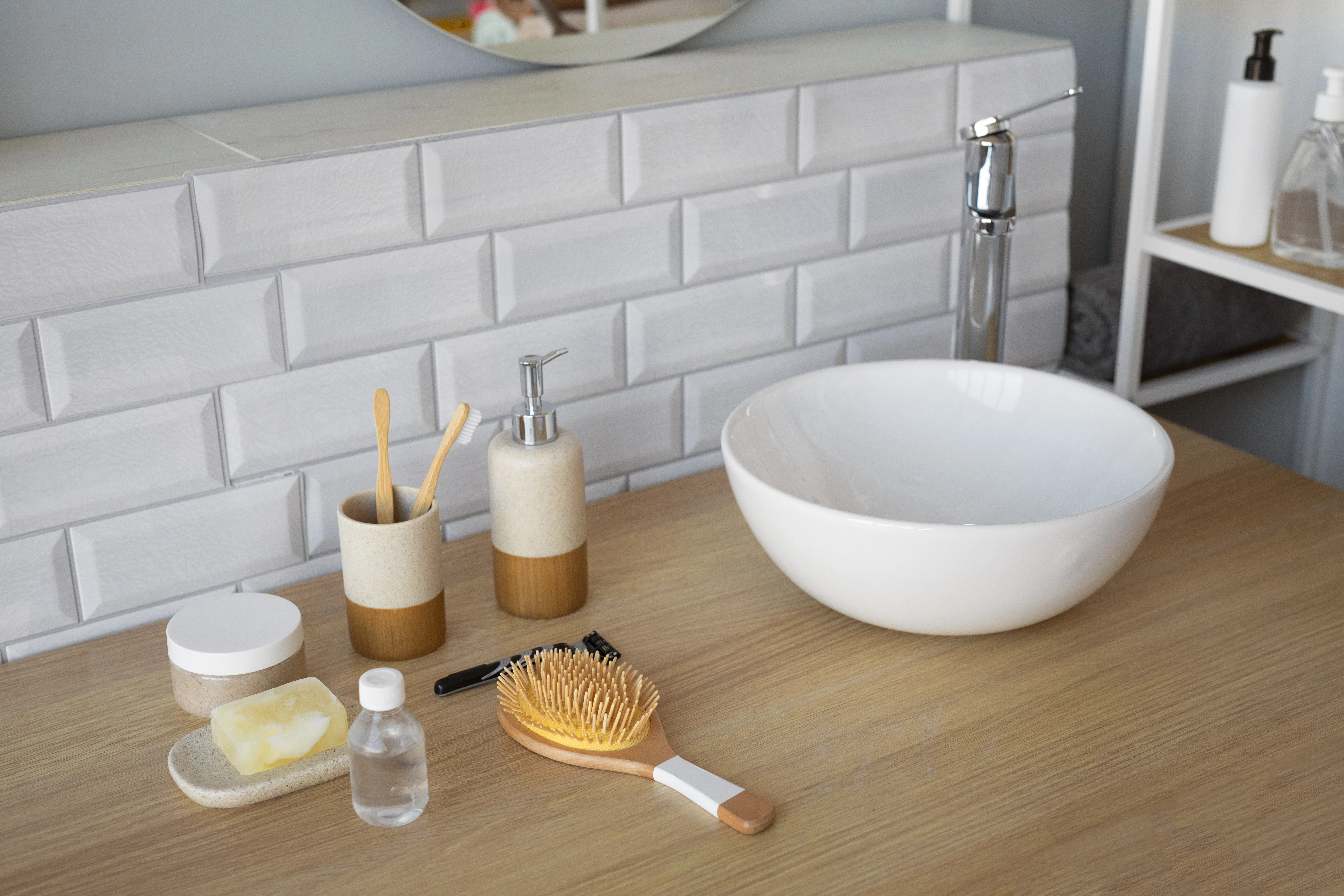 Salle de bain avec plan vasque en bois, vasque ronde blanche, robinet chromé et crédence en carrelage métro blanc.