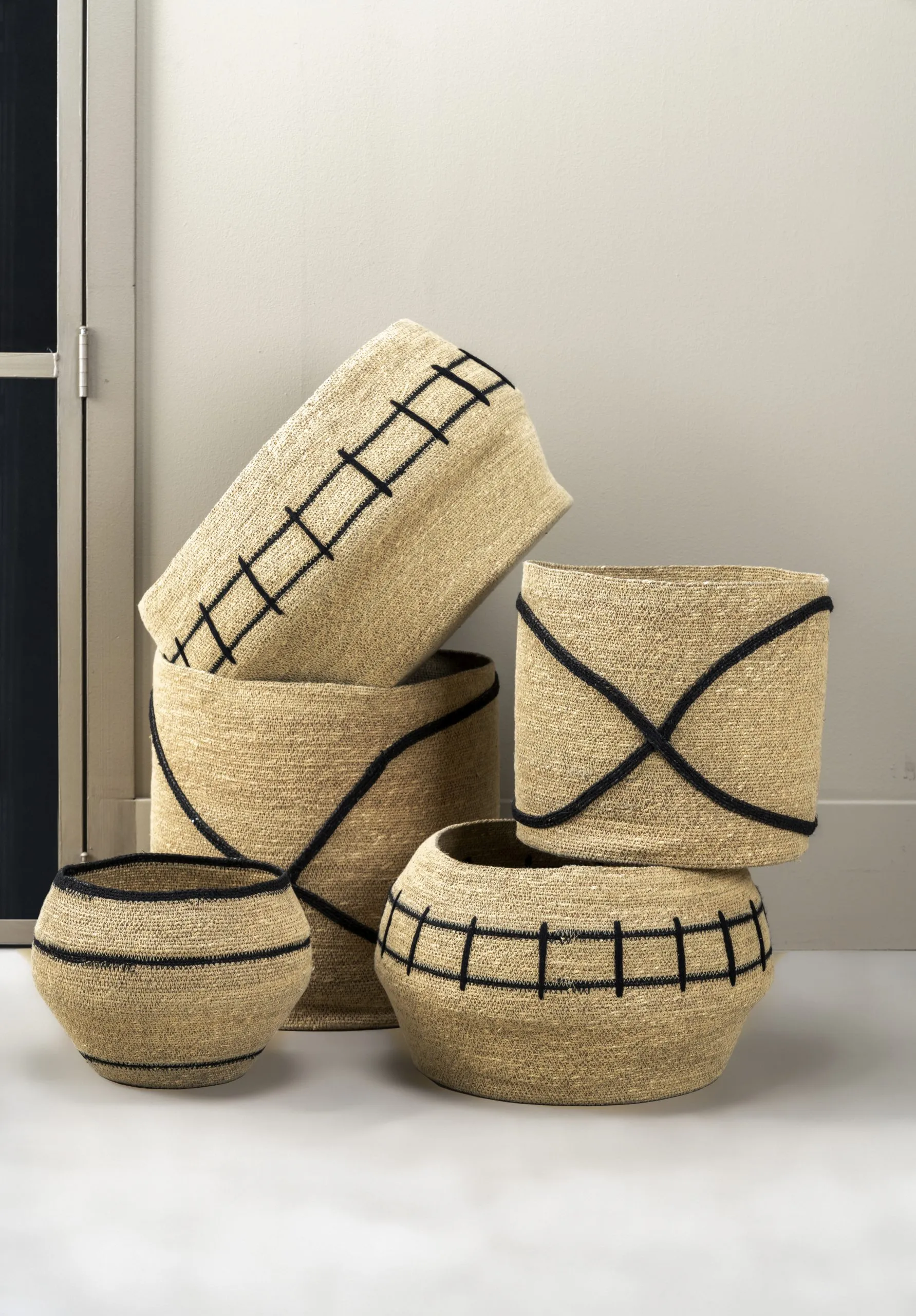 Ensemble de paniers décoratifs en fibres naturelles avec motifs noirs, idéal pour une décoration intérieure authentique.
