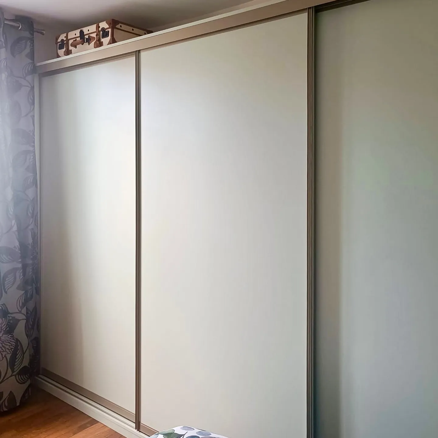 Grand placard sur-mesure avec portes coulissantes claires, installé dans une chambre avec rangements toute hauteur.