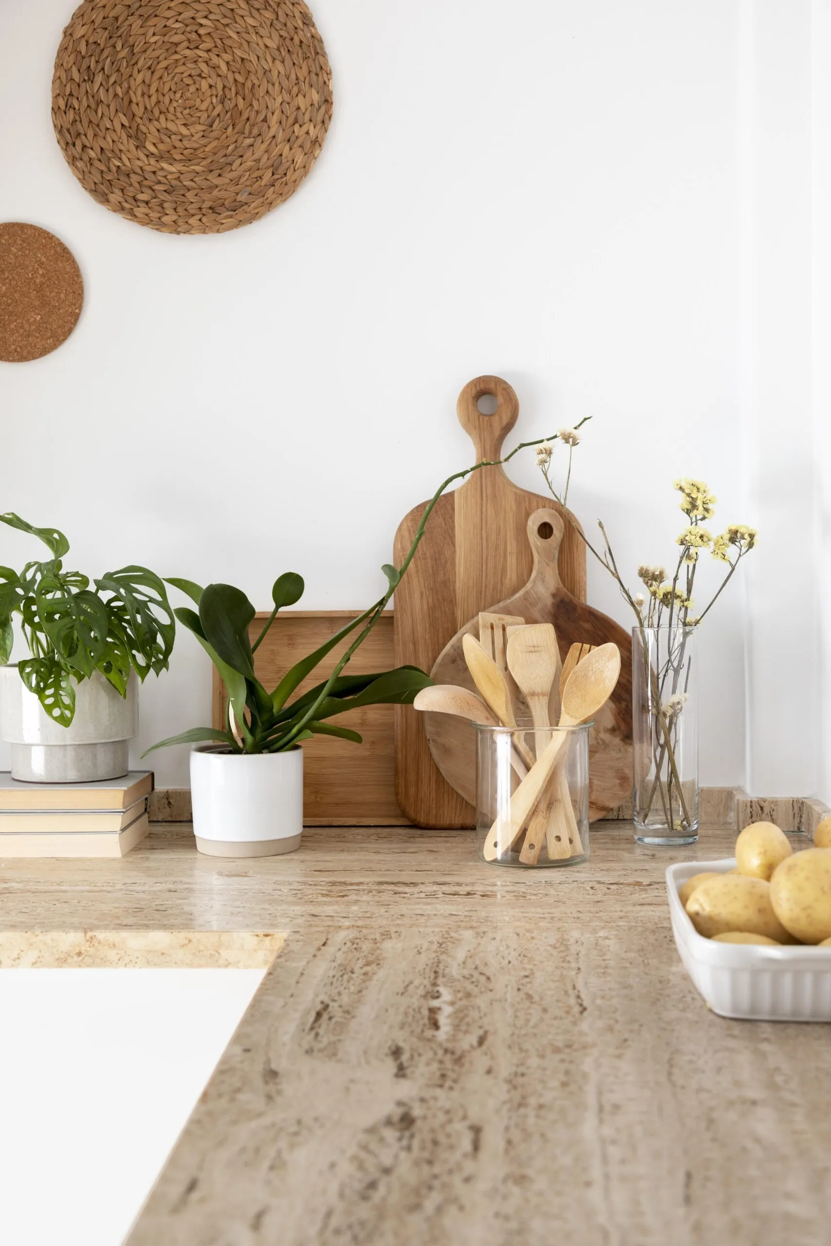 Plan de travail clair avec plantes, planches en bois, ustensiles et accessoires décoratifs dans une cuisine lumineuse à l’esprit naturel.