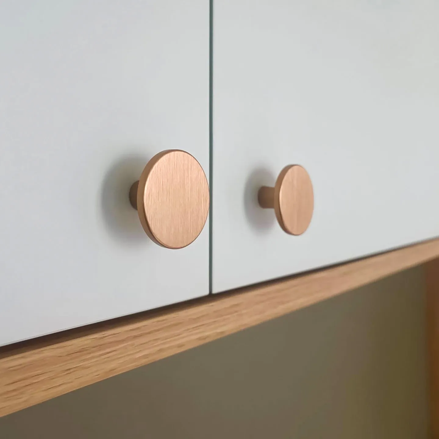Détail de poignées rondes en bois sur façades claires d’un placard de chambre sur-mesure.
