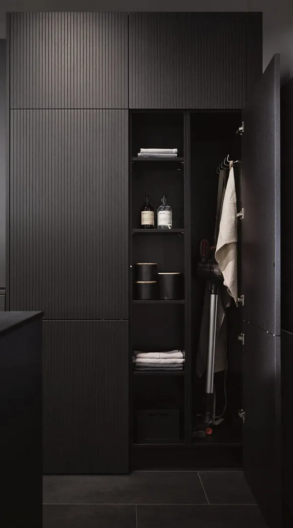 Rangement intégré noir avec façades rainurées, compartiments intérieurs, étagères ouvertes et espace dédié aux accessoires du quotidien.