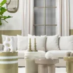Salon lumineux avec canapé blanc, tables d’appoint arrondies, coussins et objets décoratifs dans une ambiance douce et apaisante.