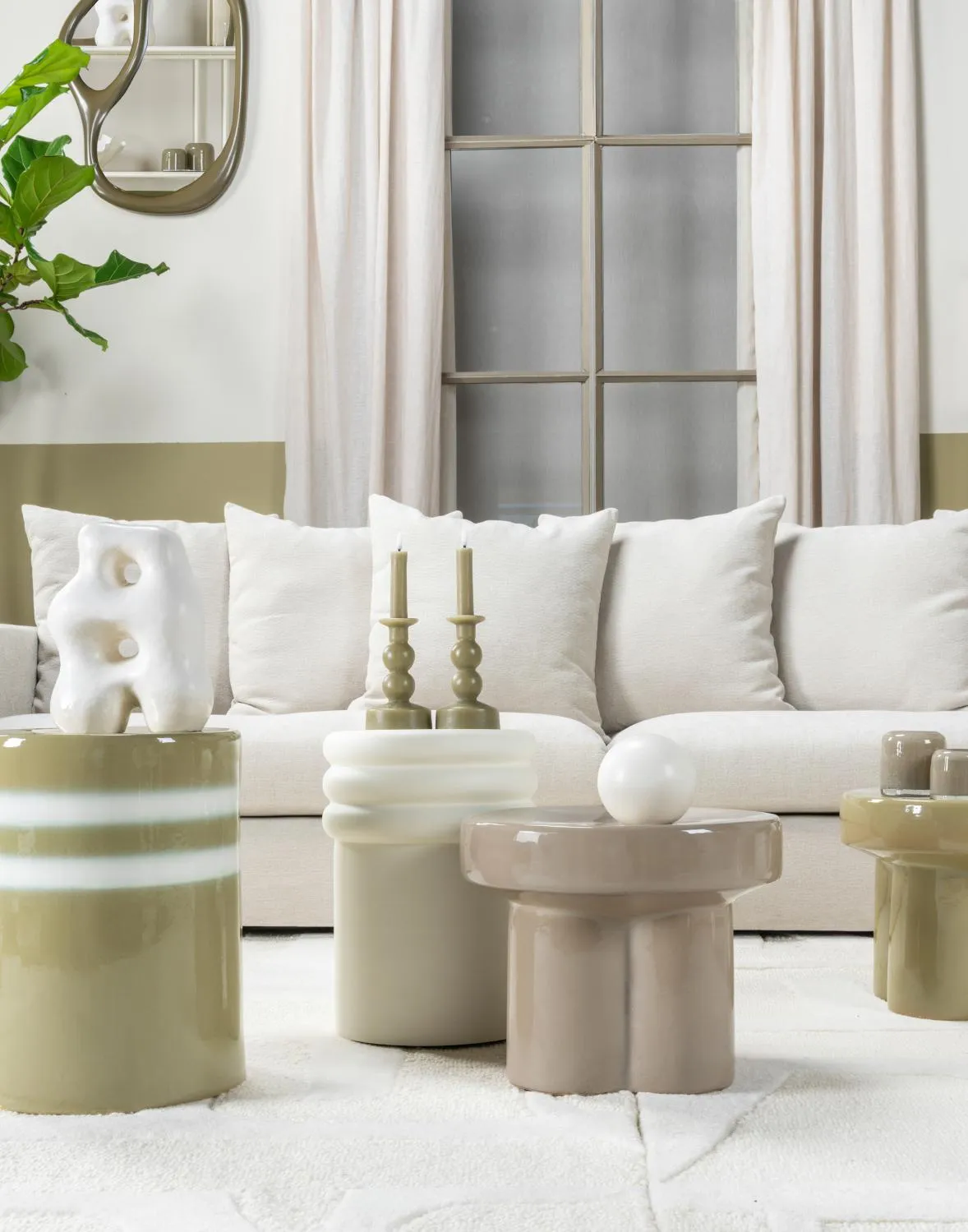 Salon lumineux avec canapé blanc, tables d’appoint arrondies, coussins et objets décoratifs dans une ambiance douce et apaisante.
