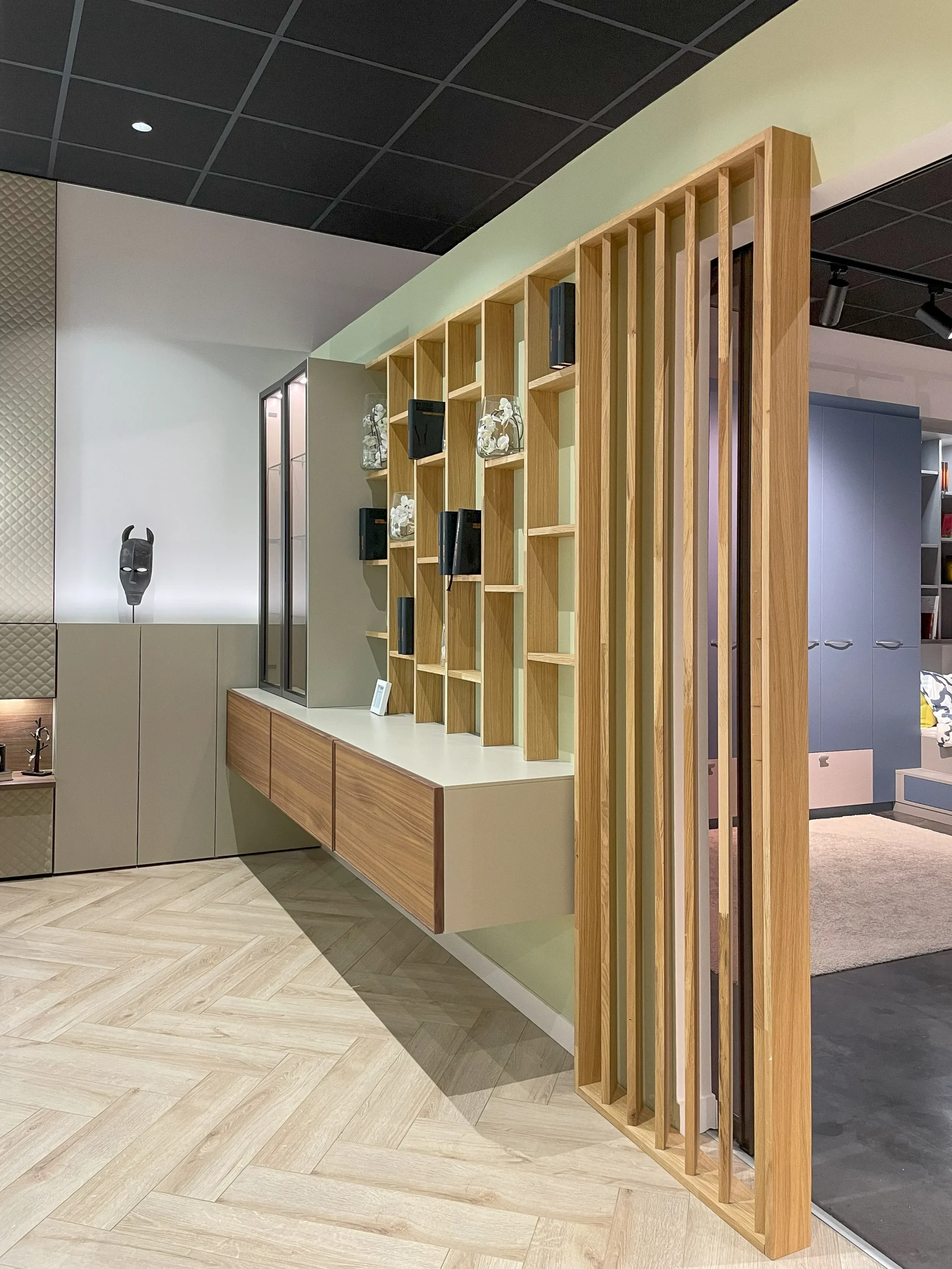 Claustra bois sur-mesure associé à une bibliothèque murale et à des rangements suspendus pour structurer l’espace avec élégance.