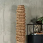 Suspension en fibres naturelles tressées devant un mur texturé, avec mobilier noir et objets décoratifs.
