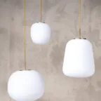 Trio de suspensions en verre opalin avec finitions laiton, idéal pour apporter une lumière douce et élégante à un intérieur.
