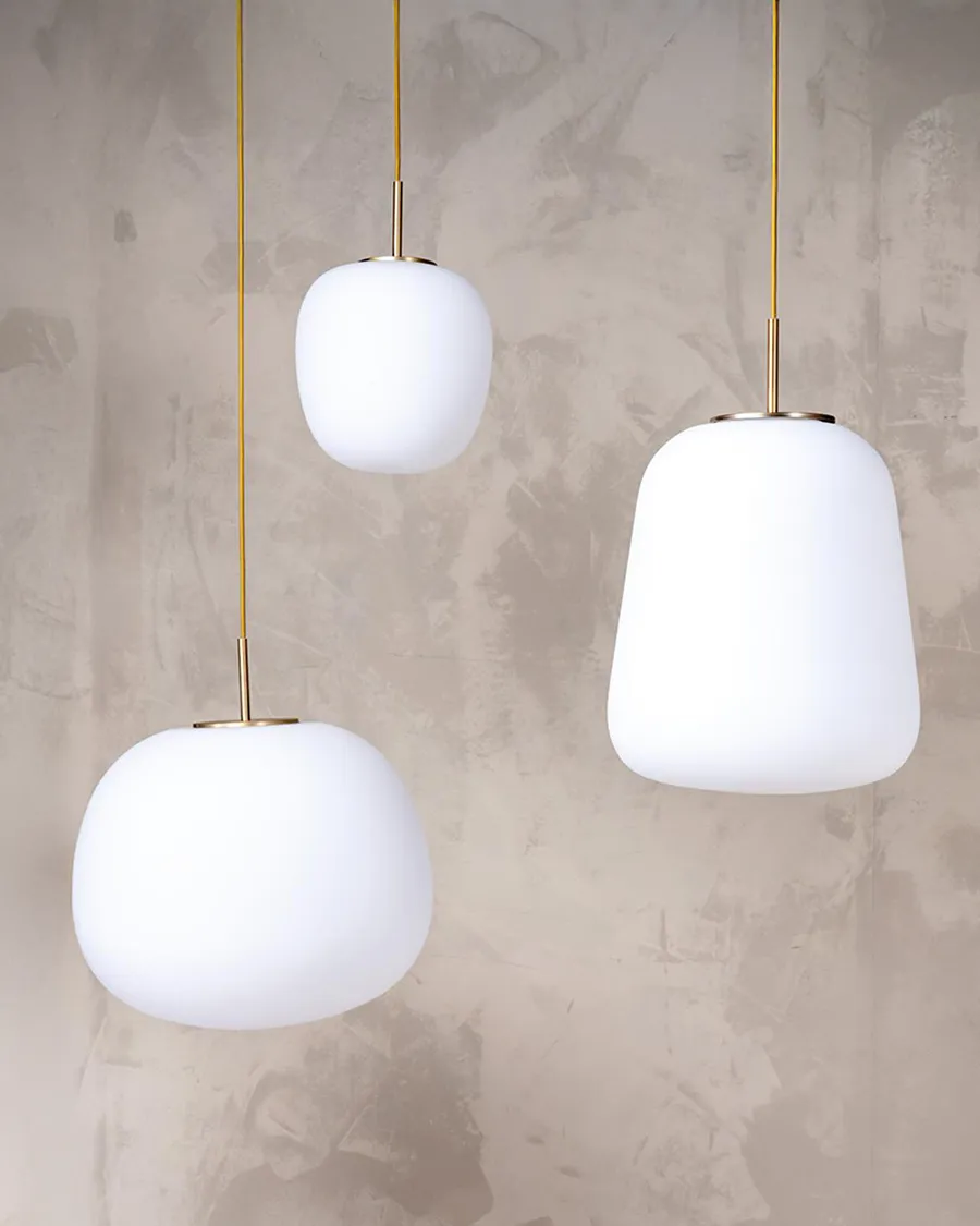 Trio de suspensions en verre opalin avec finitions laiton, idéal pour apporter une lumière douce et élégante à un intérieur.